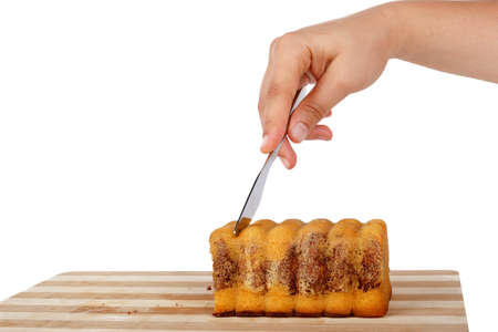 Close up detailed side view of cacao cake, woman hand slicing with a knife, isolated on white background.の写真素材