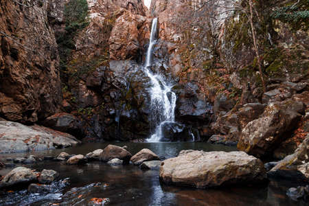 Front view of streaming waterfall with foams in deep forest in autumn season.の写真素材