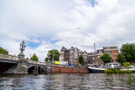 AMSTERDAM, NETHERLANDS - JULY 2, 2016 : View of architectural bridges on every canal, on cloudy sky. Amsterdam is popular with its canals.のeditorial素材