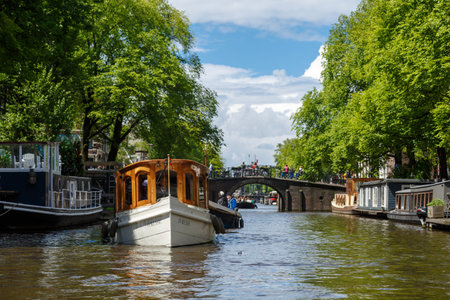AMSTERDAM, NETHERLANDS - JULY 2, 2016 : View from tours with sailboats in canals on cloudy sky. Amsterdam is popular with canal tours.のeditorial素材