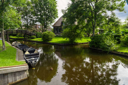 View of small sailboats in canals around trees in farm area. Giethoorn is famous village with thatcehd roof houses.の写真素材