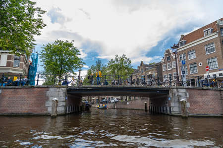 AMSTERDAM, NETHERLANDS - JULY 2, 2016 : View of architectural bridges on every canal, on cloudy sky. Amsterdam is popular with its canals.のeditorial素材