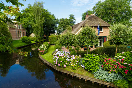 Landscape view of famous Giethoorn village with canals and rustic thatched roof houses in farm area.の写真素材