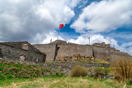 General bottom view of historical famous Kars Castle on meadow hill, Kars, Eastern Anatolia Region Turkey on cloudy sky background.のeditorial素材