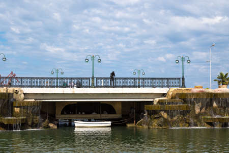 SAMSUN, TURKEY - SEPTEMBER 03, 2016 : General landscape view of small lake with artificial waterfall among bench and seats in natural park on cloudy sky background.のeditorial素材
