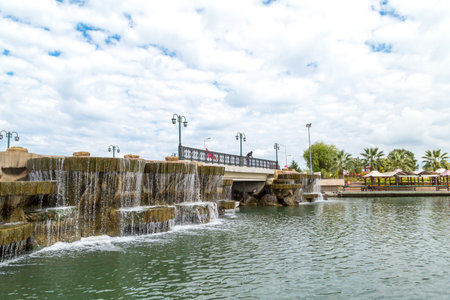SAMSUN, TURKEY - SEPTEMBER 03, 2016 : General landscape view of small lake with artificial waterfall among bench and seats in natural park on cloudy sky background.のeditorial素材