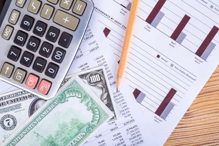 Finance and business concept, hundred dollar banknotes with pencil and calculator on graph chart analytics.の写真素材