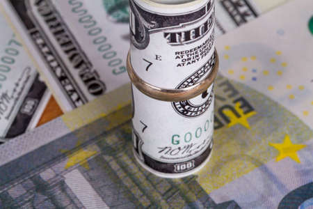 Dollar and euro banknotes with marriage ring in finance and marriage expenses concept.の写真素材