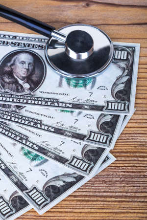 Stethoscope on one hundred dollar banknotes in healthcare budget concept.の写真素材