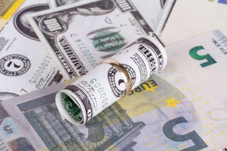 Dollar and euro banknotes with marriage ring in finance and marriage expenses concept.の写真素材