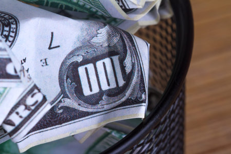 Dollar banknotes crumpled inside garbage basket, rubbish bin focused on consuming money in finance concept, on wooden background.の写真素材