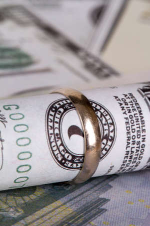 Dollar and euro banknotes with marriage ring in finance and marriage expenses concept.の写真素材