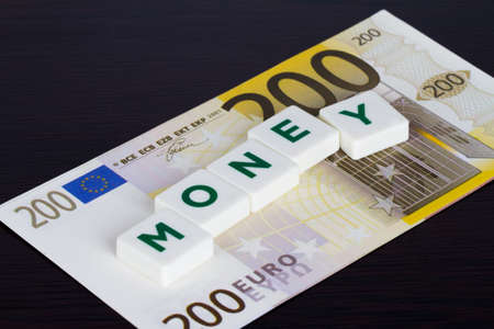 Money word with green letters and euro banknote behind on wooden background.の写真素材
