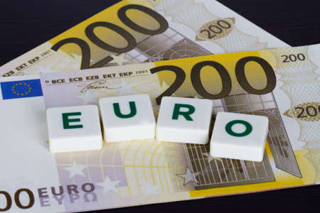 Euro word with green letters and euro banknote behind on wooden background.の写真素材