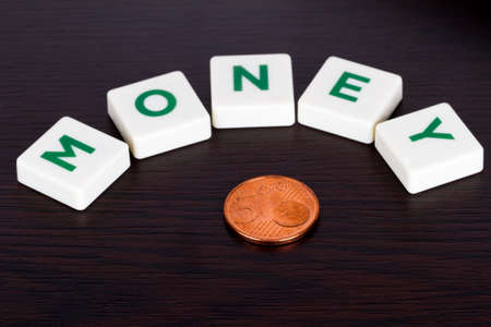 Word money with green and white letters and small coin on wooden.の写真素材
