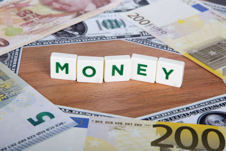 Money word with green letters among cash dollar, euro and Turkish lira banknotes on wooden.の写真素材