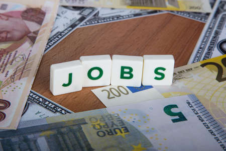 Jobs word with green letters among cash dollar, euro and Turkish lira banknotes on wooden.の写真素材