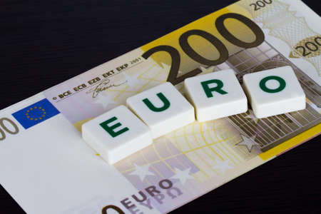 Euro word with green letters and euro banknote behind on wooden background.の写真素材