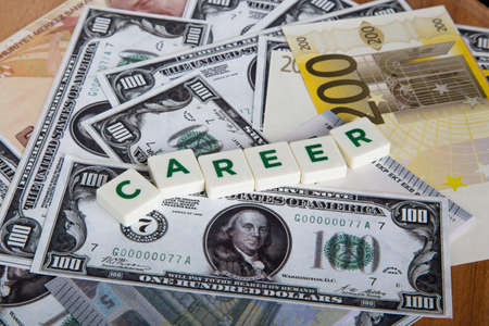 Career word with green letters among cash dollar, euro and turkish lira banknotes on wooden background.の写真素材