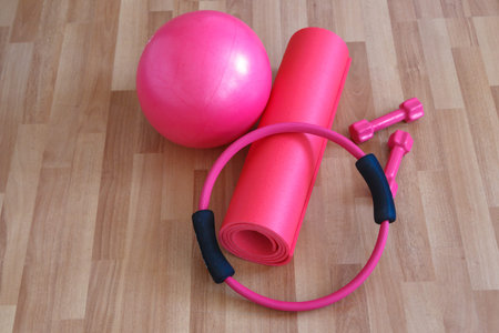 Pilates ball and circle, pink dumbbell on yoga mat, healthy life and sport concept, wooden background.の写真素材