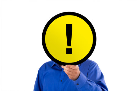 Illustrative round yellow warning signboard with exclamation mark, businessman holding on hand,...