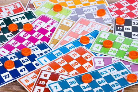 Colorful lotto or bingo game papers with numbers and plastic lotto barrels, on wooden background.の写真素材