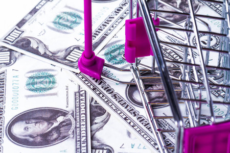 Stack of Dollar banknotes with shopping cart in money consuming concept.