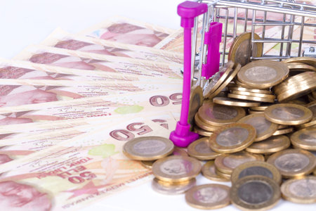 Stack of Turkish Lira banknotes and coins in shopping cart with money consuming and finance concept,...