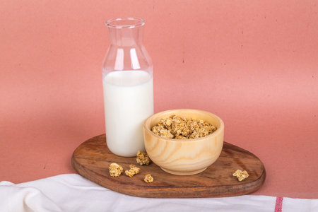 View of fit and healthy breakfast with muesli cereal in bowl and milk in bottle on background.