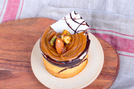Yummy tasty cake with cream, nuts and caramel sauce, served with almonds.