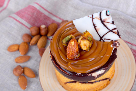 Yummy tasty cake with cream, nuts and caramel sauce, served with almonds.