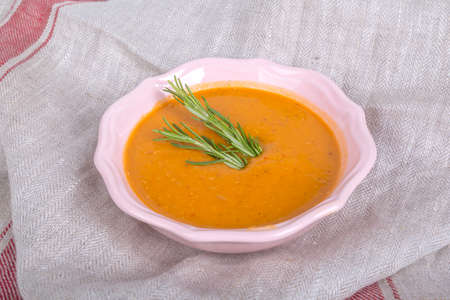 Top view of lentil soup served in pink bowl with rosemary, on dark fabric background.の写真素材