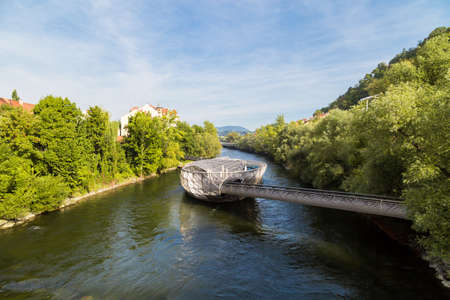 GRAZ, AUSTRIA - SEPTEMBER 16, 2016 : Exterior view of Murinsel Bridge in Graz. Designed modern architecture artificial island on Mur river with trees around in spring.のeditorial素材