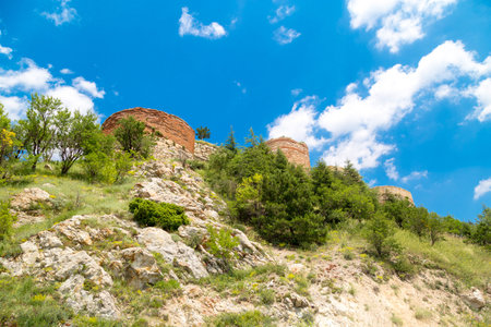 Historical Kutahya Castle with brick stone walls and bastions, at the hill surrounded with trees, on cloudy blue sky background.の写真素材