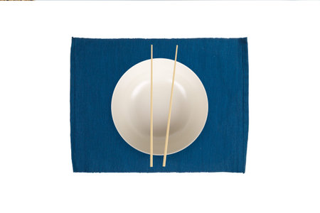 Top view of empty white plate with chopsticks on mat, isolated on white background.の写真素材