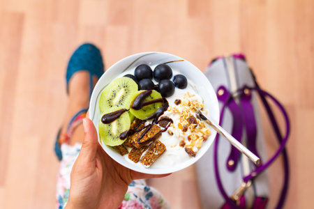 Business woman holding and eating raw vegan energy bites, bars and fruits in cup. Lifestyle healthy...