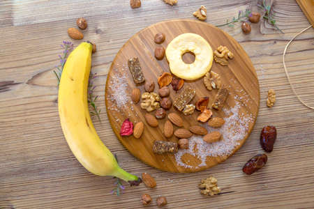 Top view of mixed food and nuts with fruits, served on wooden plate.の写真素材