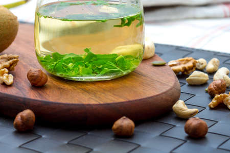 Healthy snack eating and drinking concept with green tea and mix of nuts, raw bars, fruits, served on wooden plate.の写真素材