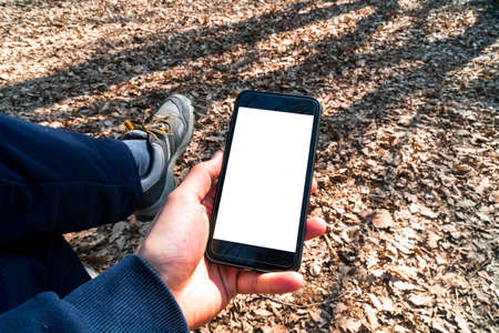 Mockup image of smart phone with white blank screen template, hand holding and showing mobile in nature outdoor.の写真素材