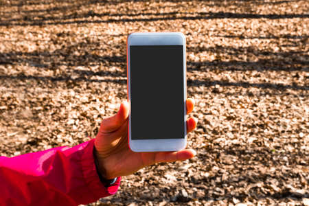 Mockup image of smart phone with black blank screen template, hand holding and showing mobile in nature outdoor.の写真素材