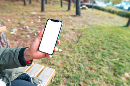 Woman hand holding and showing mobile in nature outdoor.の写真素材