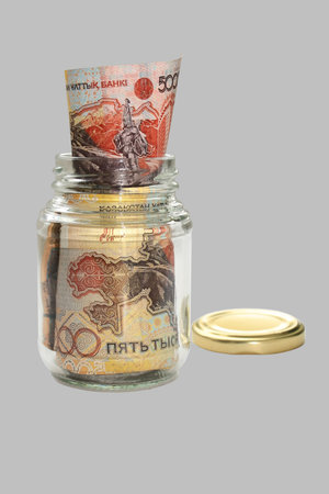 Money Kazakhstan. Packed in a glass jar. Close-up. Isolation on a gray background.