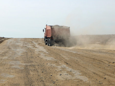 loaded truck is driving along a dirt road.