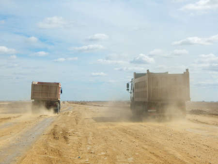 loaded truck is driving along a dirt road.の写真素材