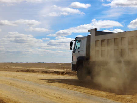 loaded truck is driving along a dirt road.の写真素材