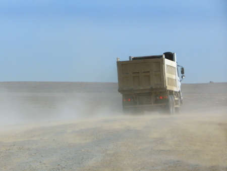 loaded truck is driving along a dirt road.の写真素材