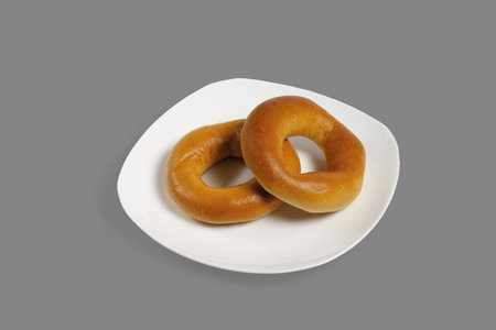 Bagels on a white plate. Isolated on gray background.