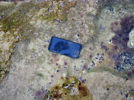 Smartphone under water. Damaged smartphone drowned in the sea.
