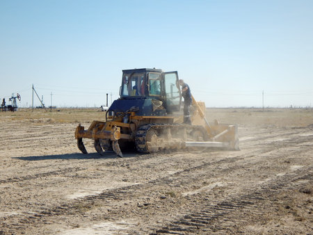Tractor driver cleans a bulldozer. Bulldozer in the steppes level the site. Kazakhstan. Oil field....
