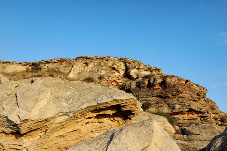 The rugged landscape features layered rock formations under a bright blue sky. The natural scenery showcases the textures of the earth, creating a serene atmosphere.の写真素材